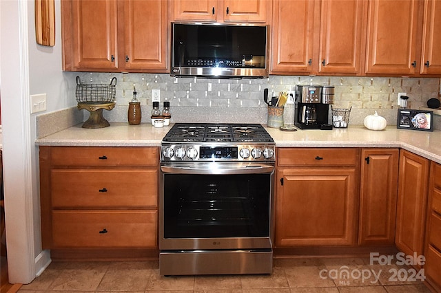 kitchen featuring stainless steel appliances, light tile patterned floors, and backsplash