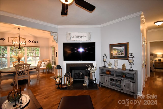 living room with ornamental molding, ceiling fan with notable chandelier, and dark hardwood / wood-style flooring