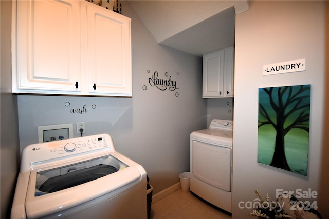 laundry room featuring washing machine and dryer, light tile patterned floors, and cabinets