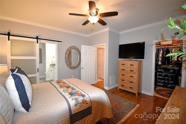 bedroom featuring ceiling fan, a barn door, wood-type flooring, connected bathroom, and a closet