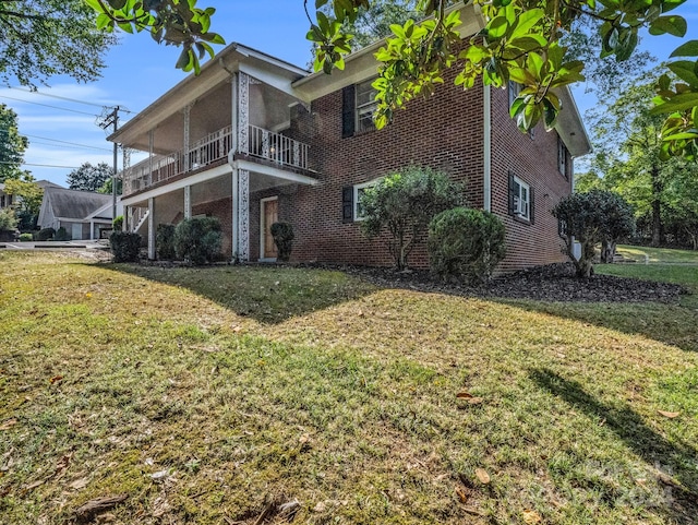 view of home's exterior with a balcony and a yard