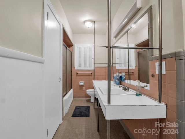 full bathroom with sink, toilet, enclosed tub / shower combo, tile patterned floors, and tile walls