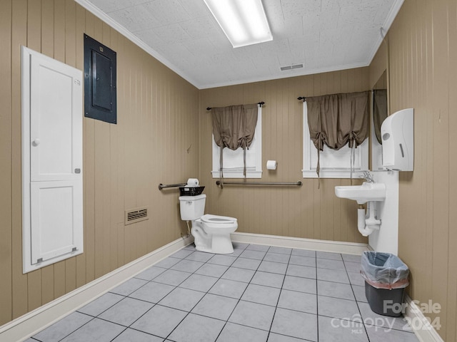 bathroom featuring toilet, electric panel, wooden walls, and tile patterned flooring