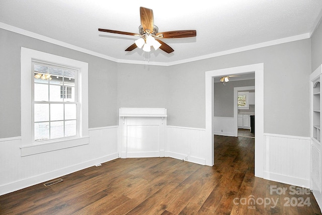 empty room with ornamental molding, a textured ceiling, dark wood-type flooring, and ceiling fan