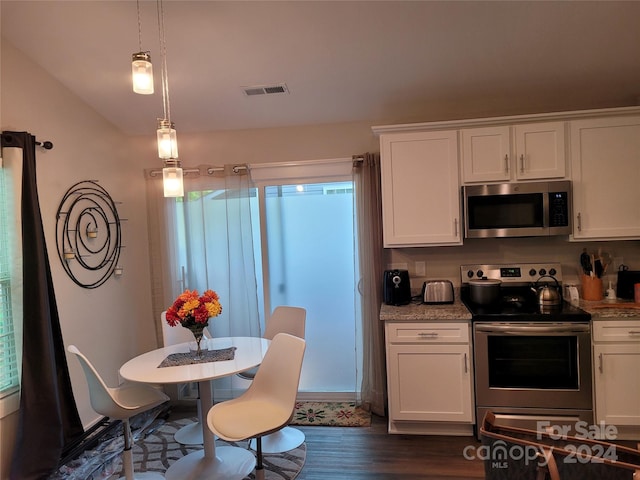 kitchen with white cabinets, stainless steel appliances, pendant lighting, and dark hardwood / wood-style floors