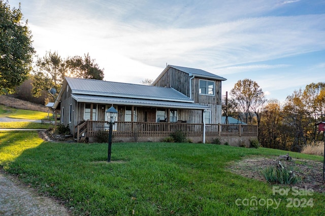 rear view of property featuring a lawn and a porch