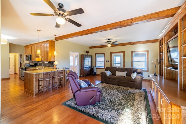 living room featuring ceiling fan, hardwood / wood-style flooring, beamed ceiling, and sink