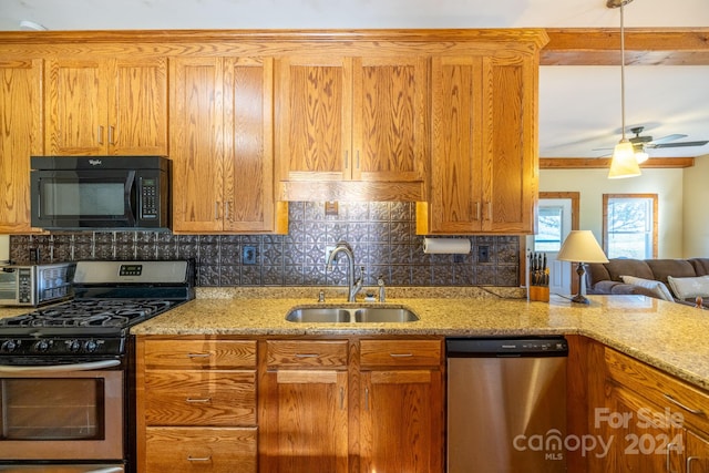 kitchen featuring stainless steel appliances, backsplash, sink, light stone countertops, and ceiling fan