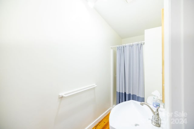 bathroom featuring hardwood / wood-style flooring, a shower with curtain, and vaulted ceiling