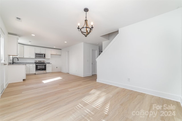 unfurnished living room with an inviting chandelier, sink, and light wood-type flooring