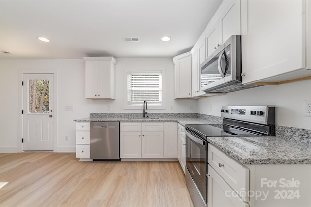 kitchen with a healthy amount of sunlight, appliances with stainless steel finishes, sink, and white cabinets