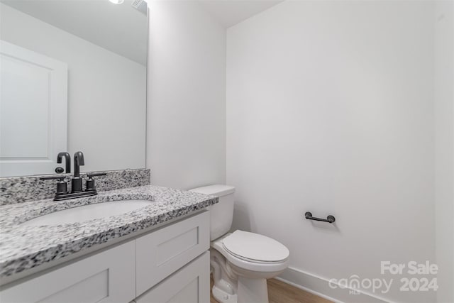 bathroom with toilet, hardwood / wood-style flooring, and vanity