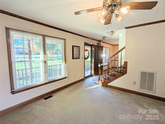 foyer entrance with carpet floors, visible vents, crown molding, and a textured ceiling