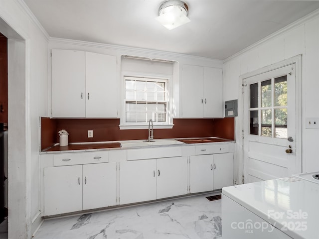 kitchen featuring crown molding, marble finish floor, white cabinets, and a sink