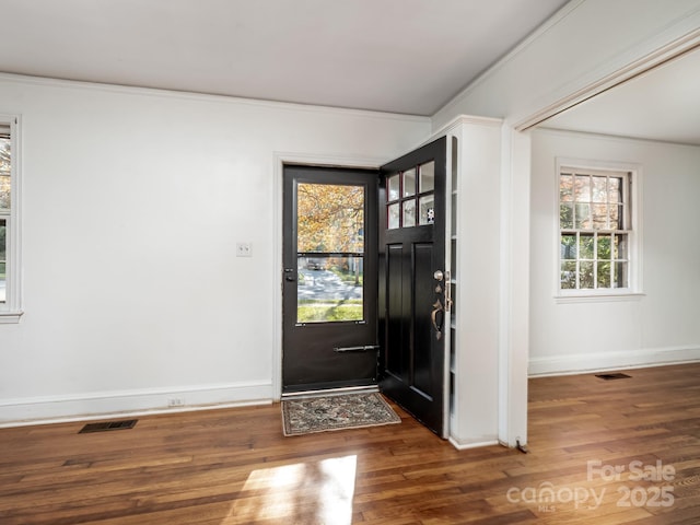 foyer with visible vents, crown molding, and wood finished floors