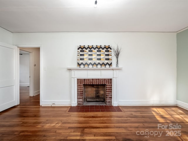 unfurnished living room with a brick fireplace, wood finished floors, and baseboards