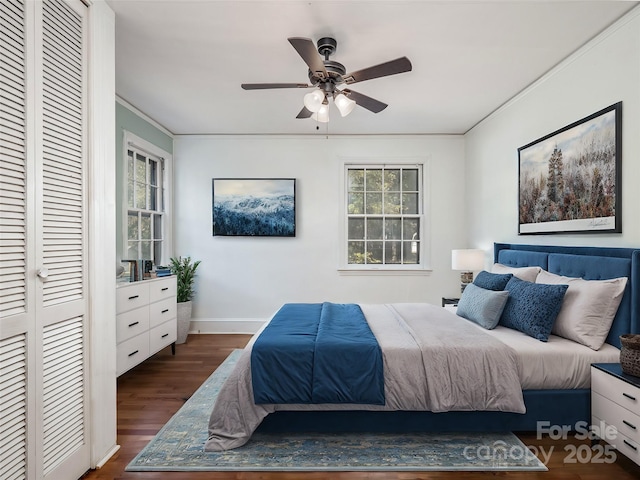 bedroom with a closet, ornamental molding, ceiling fan, wood finished floors, and baseboards