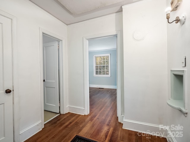 corridor with crown molding, baseboards, and wood finished floors