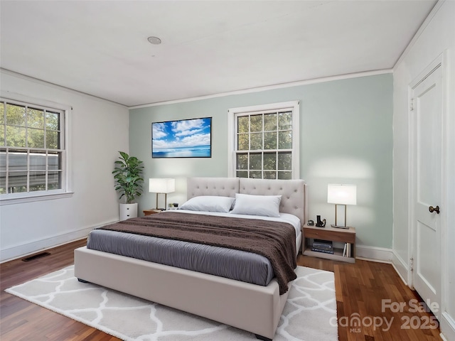 bedroom featuring crown molding, wood finished floors, visible vents, and baseboards