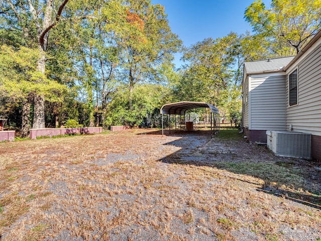 view of yard with a carport, driveway, and central AC unit