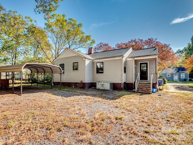 back of house featuring a chimney and a carport