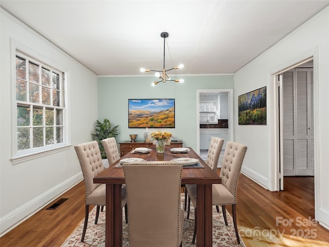 dining space featuring ornamental molding, dark hardwood / wood-style floors, and an inviting chandelier