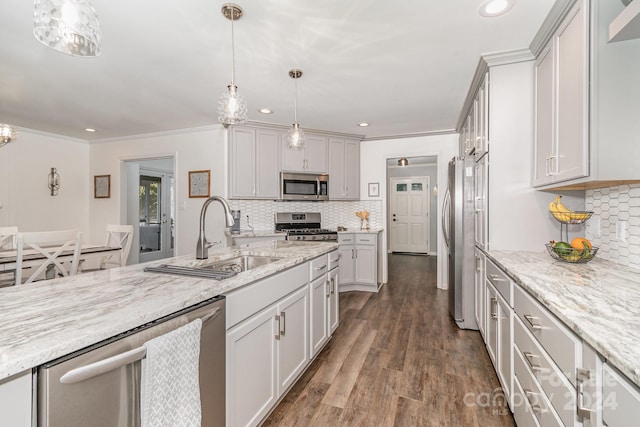 kitchen with appliances with stainless steel finishes, sink, pendant lighting, ornamental molding, and dark hardwood / wood-style floors