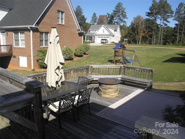 wooden terrace featuring a lawn, a playground, and an outdoor fire pit