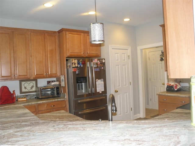 kitchen featuring pendant lighting, light stone counters, and stainless steel fridge with ice dispenser