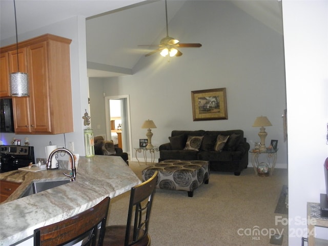 kitchen with sink, ceiling fan, a kitchen bar, high vaulted ceiling, and light colored carpet