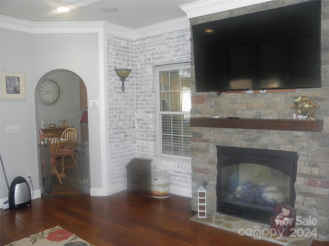 living room featuring a stone fireplace, dark hardwood / wood-style floors, and crown molding