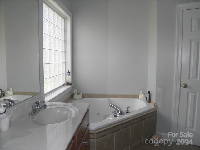 bathroom with plenty of natural light, vanity, tiled tub, and tile patterned floors