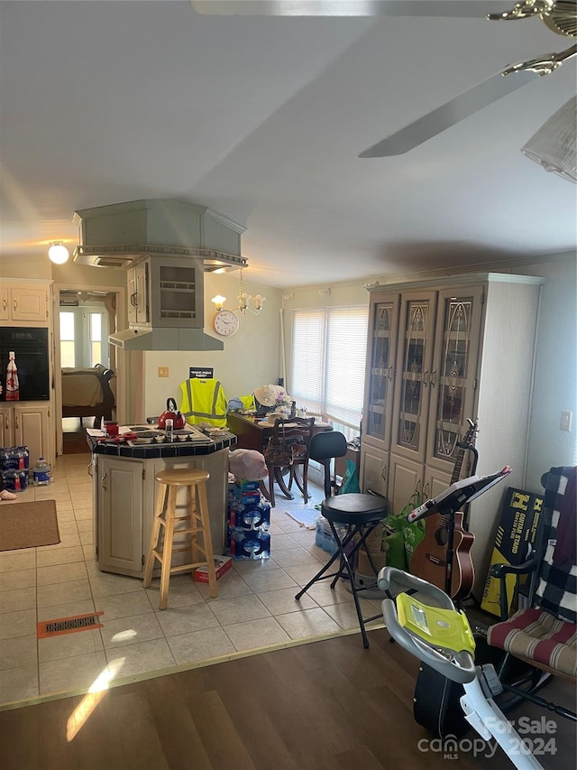 kitchen featuring a kitchen island, oven, tile countertops, a breakfast bar area, and light wood-type flooring