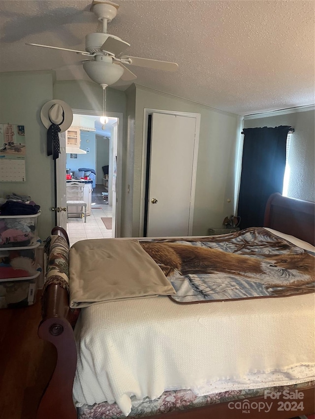 bedroom featuring a textured ceiling, vaulted ceiling, and ceiling fan