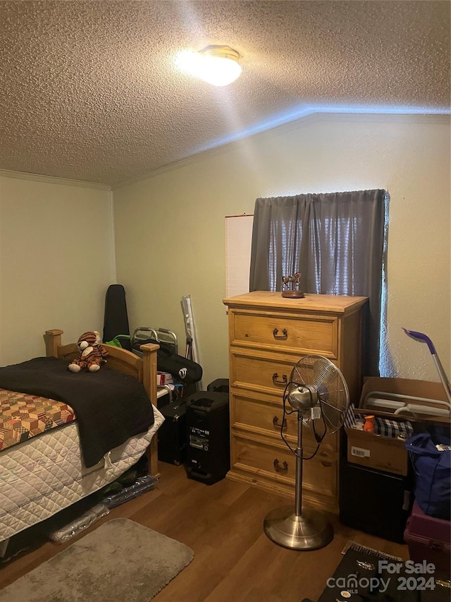 bedroom with a textured ceiling, vaulted ceiling, and hardwood / wood-style floors