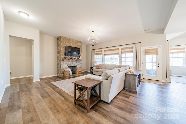 living room with light hardwood / wood-style floors, a stone fireplace, and a healthy amount of sunlight