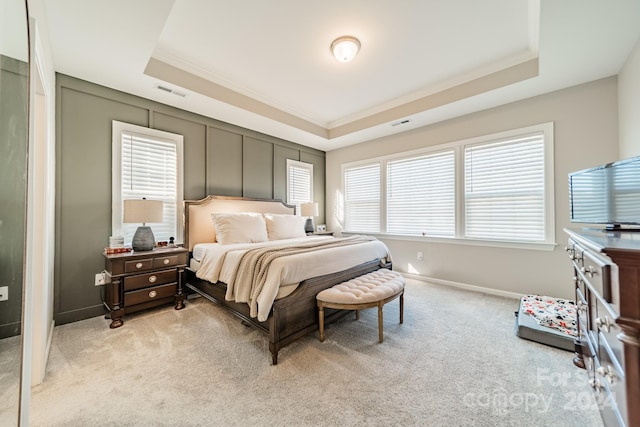 carpeted bedroom featuring a tray ceiling, multiple windows, and crown molding