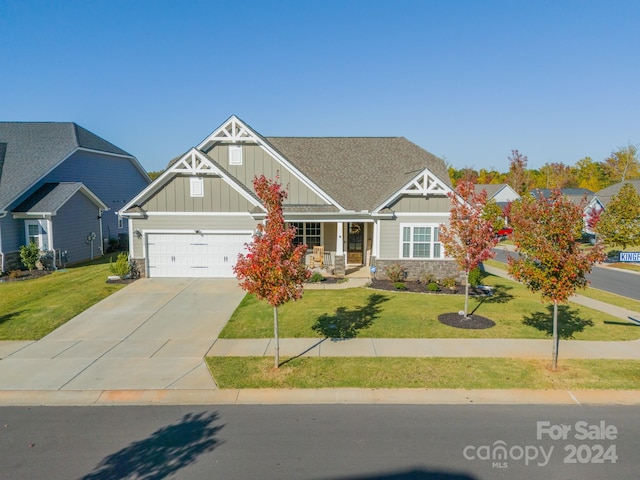 craftsman inspired home with covered porch, a garage, and a front yard