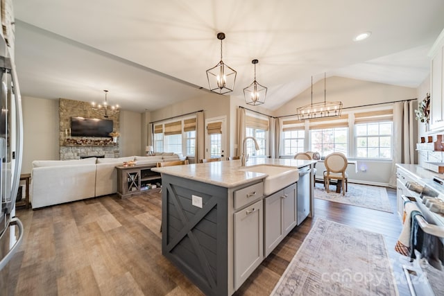 kitchen with sink, decorative light fixtures, plenty of natural light, and an island with sink