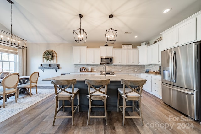 kitchen featuring dark hardwood / wood-style flooring, stainless steel appliances, white cabinetry, and a kitchen island with sink