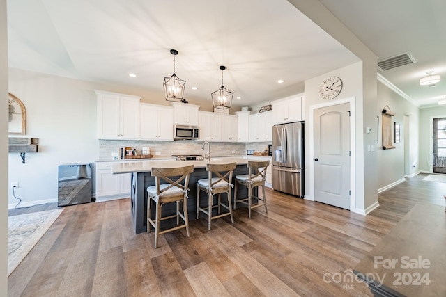 kitchen featuring white cabinets, appliances with stainless steel finishes, light hardwood / wood-style floors, and a kitchen island with sink