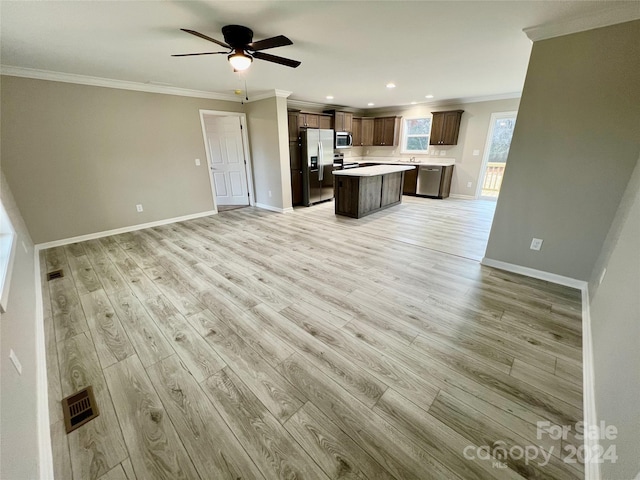 kitchen with a center island, ceiling fan, ornamental molding, appliances with stainless steel finishes, and light hardwood / wood-style floors