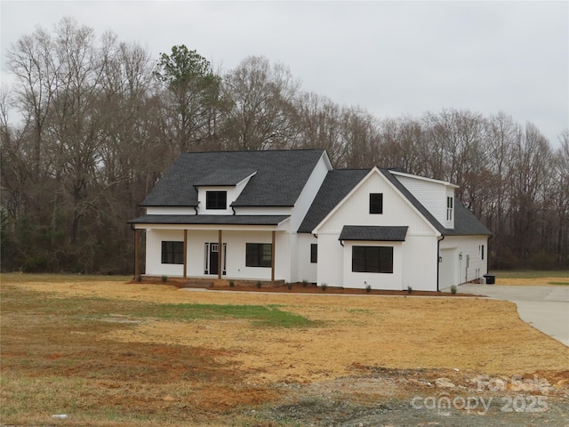 modern farmhouse style home featuring driveway, a shingled roof, a front lawn, and a porch