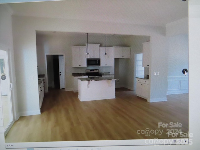 kitchen with dark countertops, a kitchen island, appliances with stainless steel finishes, white cabinetry, and pendant lighting