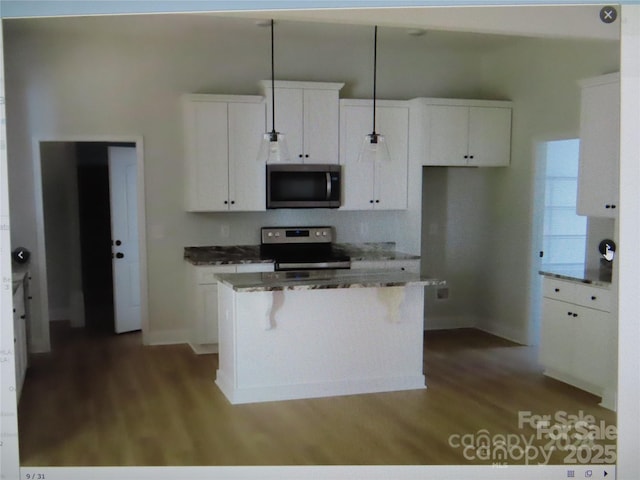 kitchen featuring hanging light fixtures, appliances with stainless steel finishes, white cabinets, and a center island