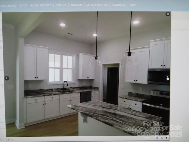 kitchen with stainless steel appliances, dark countertops, white cabinetry, and decorative light fixtures