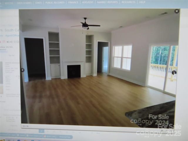 unfurnished living room featuring built in features, a fireplace, a ceiling fan, and wood finished floors