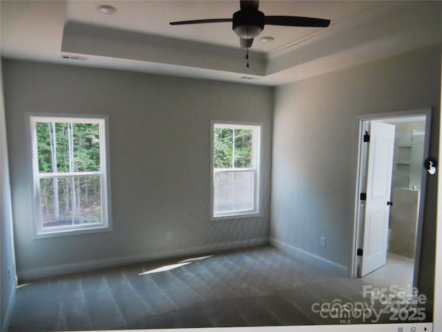 unfurnished room featuring a ceiling fan, visible vents, baseboards, a tray ceiling, and carpet