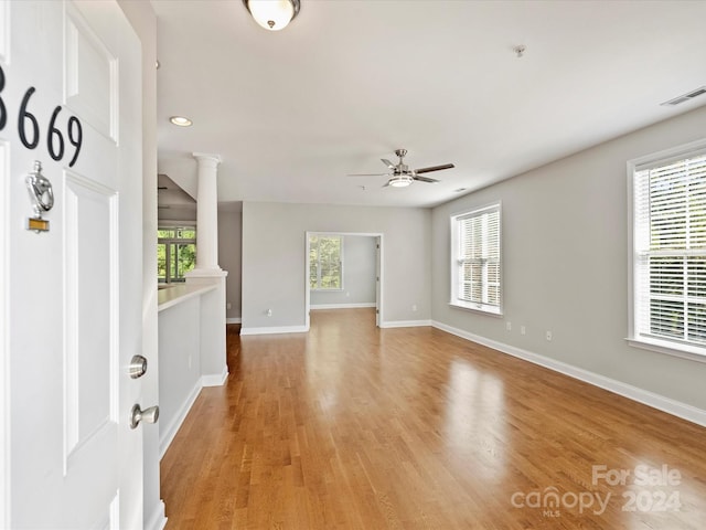 interior space with decorative columns, light hardwood / wood-style flooring, and ceiling fan