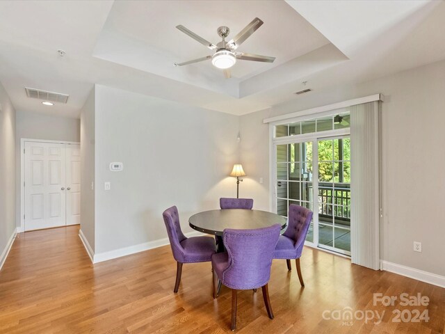 dining space featuring a tray ceiling, light wood-type flooring, and ceiling fan